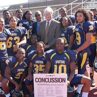 Photo of Chairman Miller with high school football team and NFL concussions poster.
